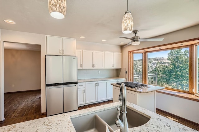 kitchen with light stone counters, stainless steel appliances, sink, pendant lighting, and white cabinets