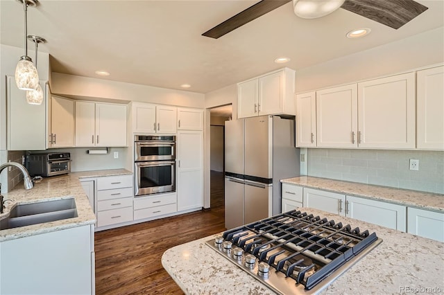 kitchen featuring stainless steel appliances, dark wood-type flooring, sink, pendant lighting, and white cabinets