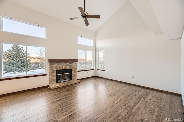 unfurnished living room with a brick fireplace, hardwood / wood-style flooring, high vaulted ceiling, and ceiling fan