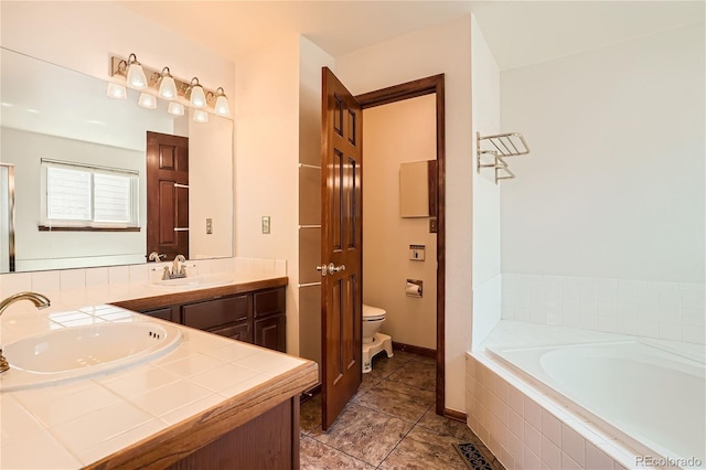 bathroom with tile patterned floors, vanity, toilet, and tiled bath