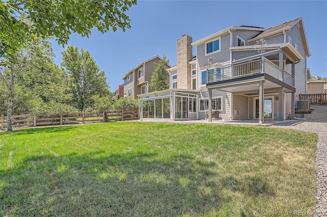 rear view of property featuring a yard, a patio area, a sunroom, and a balcony