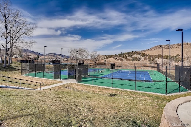 view of tennis court featuring a mountain view and a yard