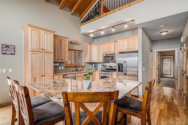 423 Prunes Pl, Fairplay, CO 80440 - kitchen with appliances with stainless steel finishes, light brown cabinetry, a kitchen breakfast bar, light stone counters, and light wood-style flooring