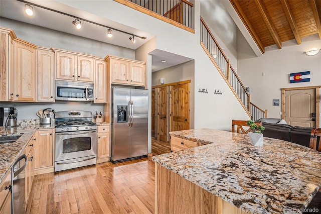 423 Prunes Pl, Fairplay, CO 80440 - kitchen featuring appliances with stainless steel finishes, light brown cabinetry, light wood-style floors, light stone counters, and a towering ceiling