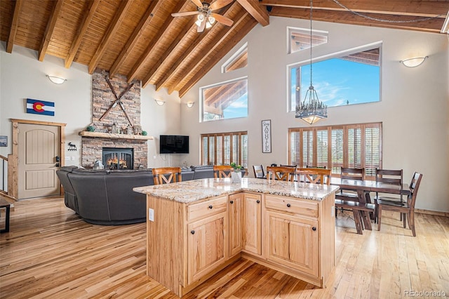 423 Prunes Pl, Fairplay, CO 80440 - kitchen featuring high vaulted ceiling, light brown cabinetry, light wood-style floors, a stone fireplace, and wood ceiling with exposed beams