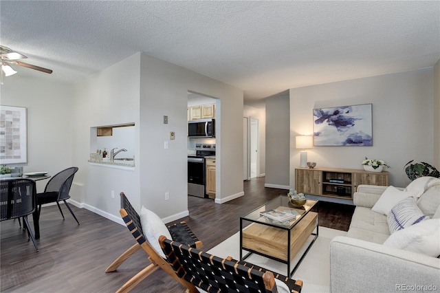 living area with dark wood finished floors, ceiling fan, a textured ceiling, and baseboards