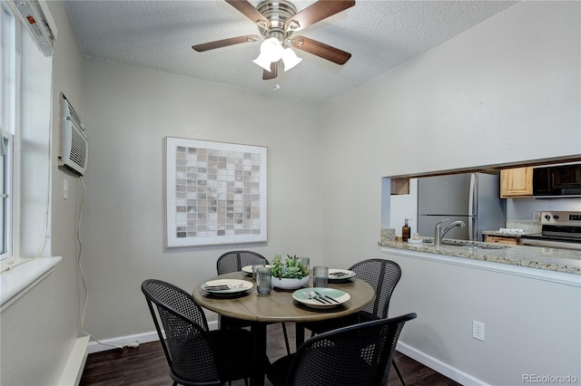 dining room featuring dark wood finished floors, baseboards, a wall mounted air conditioner, and a textured ceiling