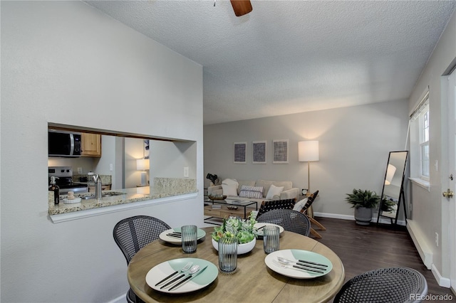 dining room with baseboards, dark wood-type flooring, ceiling fan, and a textured ceiling