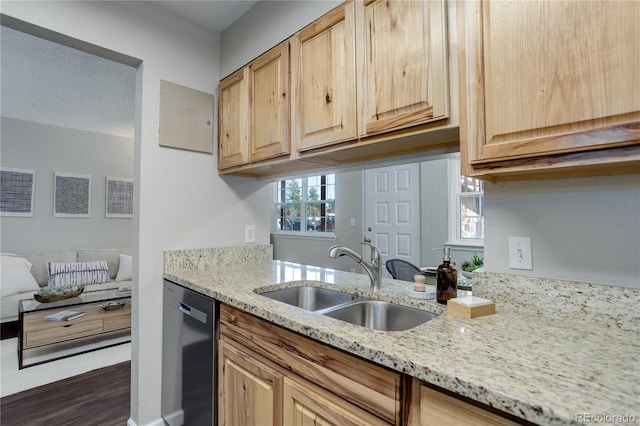 kitchen featuring dishwashing machine, light stone countertops, light brown cabinetry, and a sink