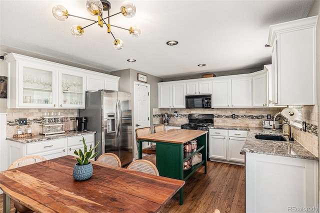 kitchen with light stone counters, dark hardwood / wood-style floors, black appliances, white cabinets, and sink