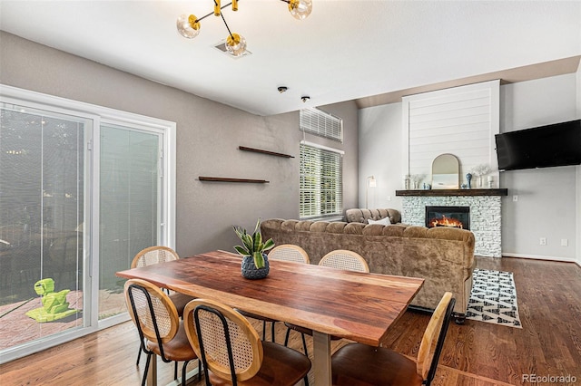 dining room featuring wood-type flooring and a stone fireplace