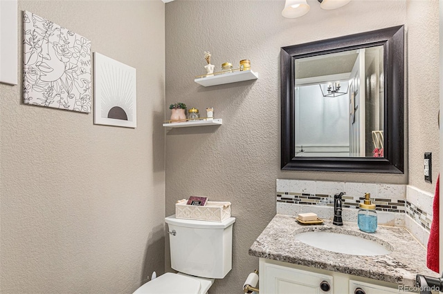 bathroom featuring toilet, vanity, and backsplash