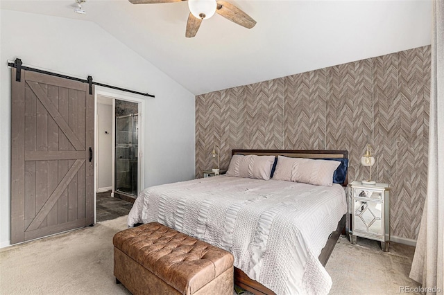 bedroom with ensuite bath, lofted ceiling, a barn door, carpet, and ceiling fan