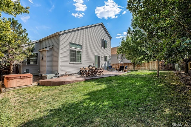 rear view of house featuring central air condition unit, a patio area, a lawn, and a hot tub