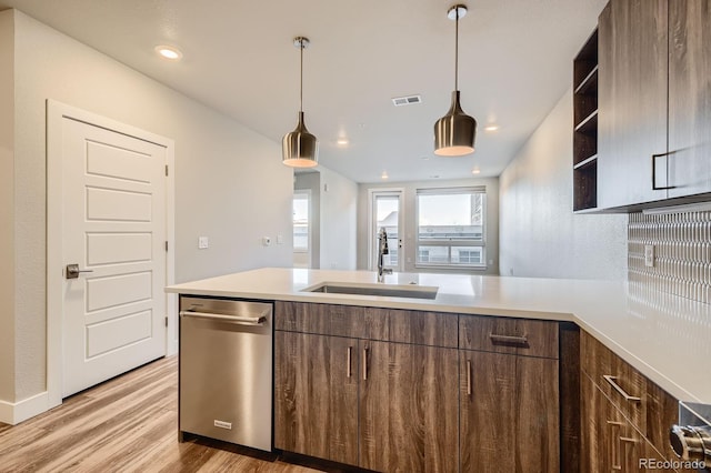 kitchen with a sink, dishwasher, light countertops, light wood-style floors, and a peninsula