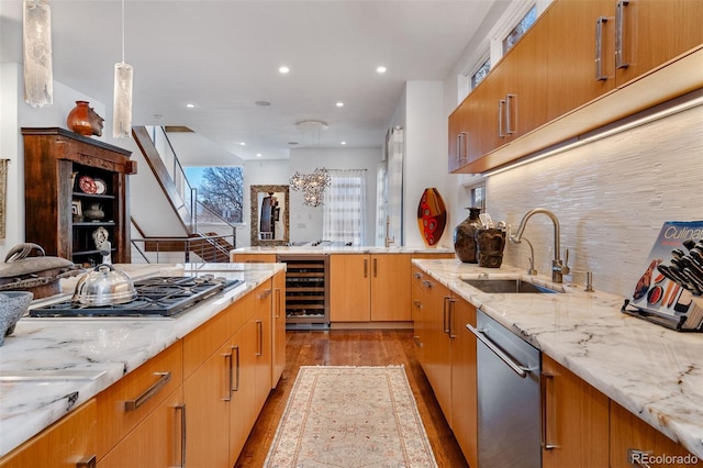 kitchen with stainless steel appliances, pendant lighting, wine cooler, and light stone counters