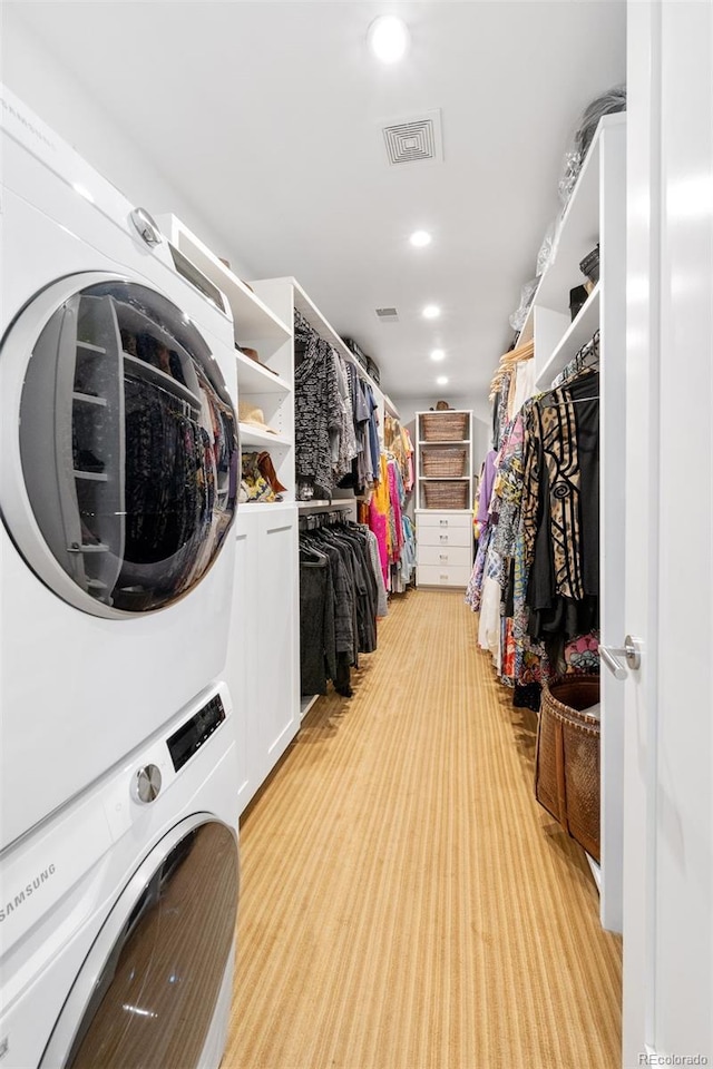 spacious closet featuring light colored carpet and stacked washing maching and dryer