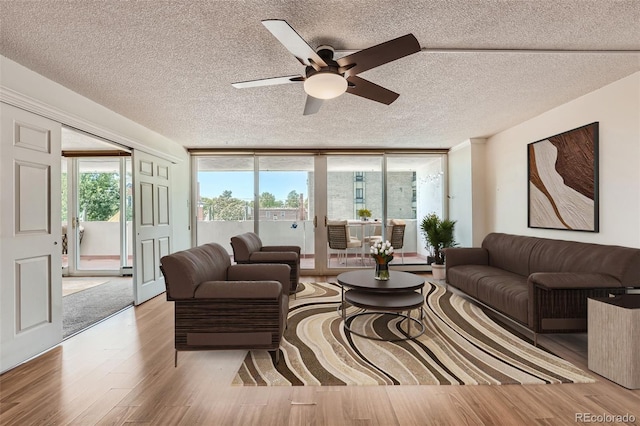 living room with a textured ceiling, light hardwood / wood-style flooring, floor to ceiling windows, and ceiling fan