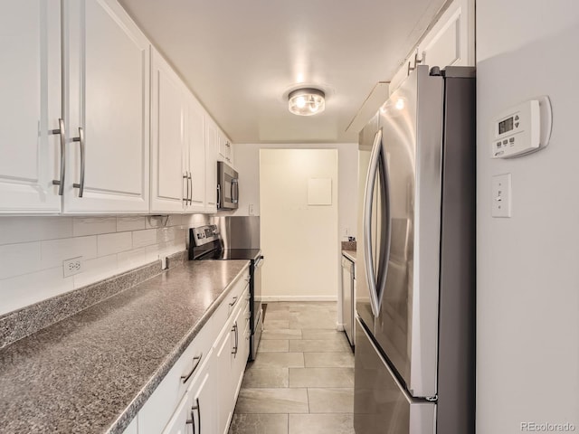 kitchen with dark stone counters, appliances with stainless steel finishes, white cabinetry, and decorative backsplash