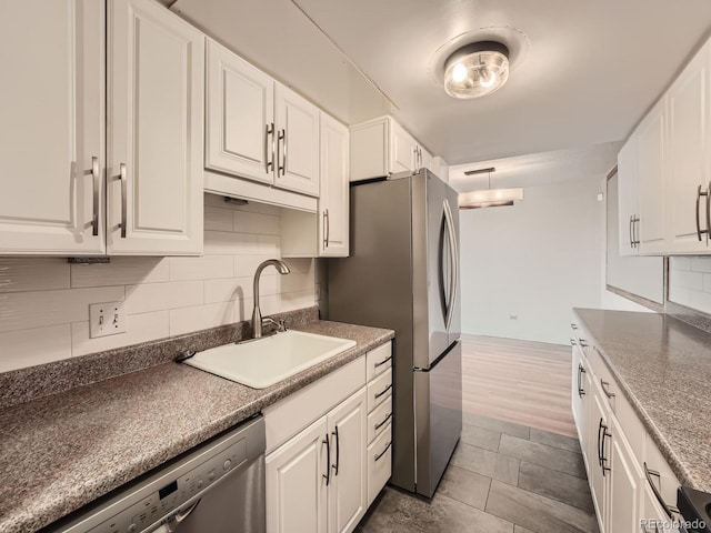 kitchen with tasteful backsplash, dark countertops, appliances with stainless steel finishes, white cabinets, and a sink