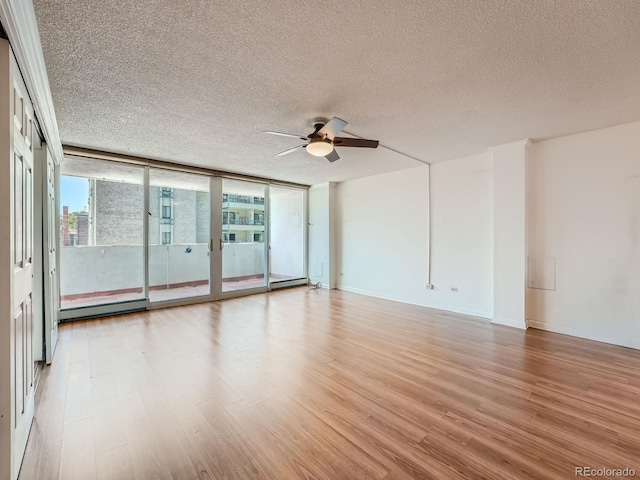 spare room featuring baseboards, a baseboard radiator, wood finished floors, expansive windows, and a textured ceiling