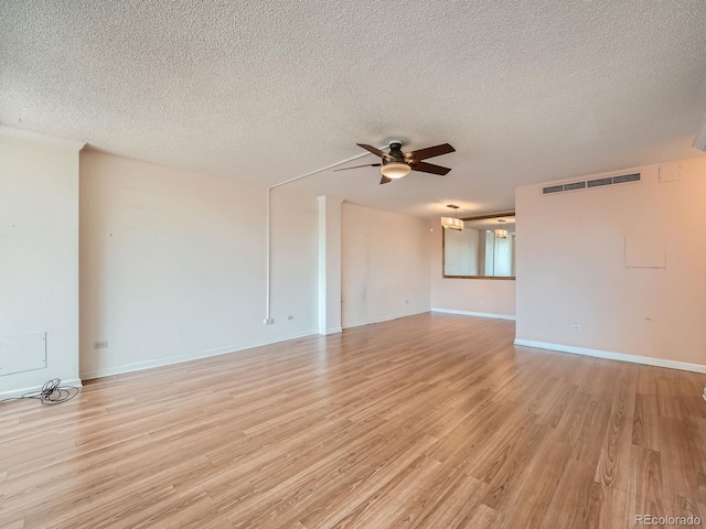 spare room with light wood finished floors, visible vents, ceiling fan, a textured ceiling, and baseboards