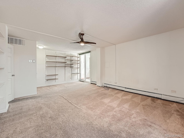 carpeted empty room featuring a ceiling fan, visible vents, a textured ceiling, and baseboard heating