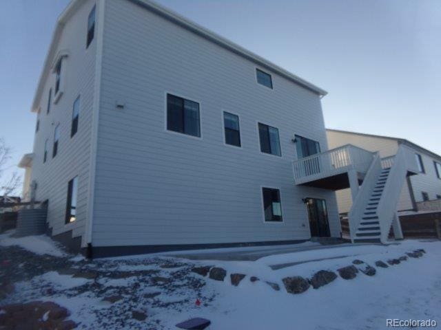 snow covered rear of property with a wooden deck