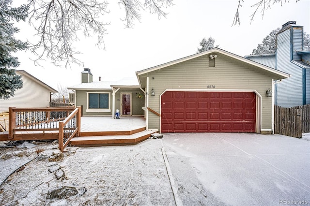 single story home with a garage, a chimney, fence, and a wooden deck