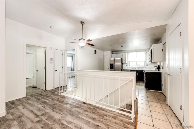 kitchen with lofted ceiling, range with electric cooktop, a sink, stainless steel refrigerator with ice dispenser, and light wood finished floors