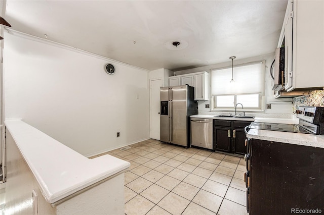 kitchen featuring light tile patterned floors, appliances with stainless steel finishes, light countertops, pendant lighting, and a sink