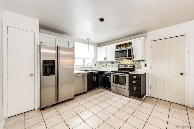 kitchen featuring light tile patterned floors, light countertops, appliances with stainless steel finishes, white cabinetry, and a sink