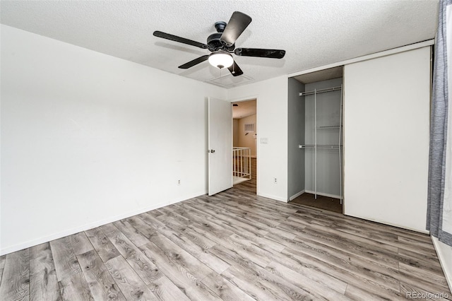 unfurnished bedroom featuring a textured ceiling, a closet, wood finished floors, and a ceiling fan