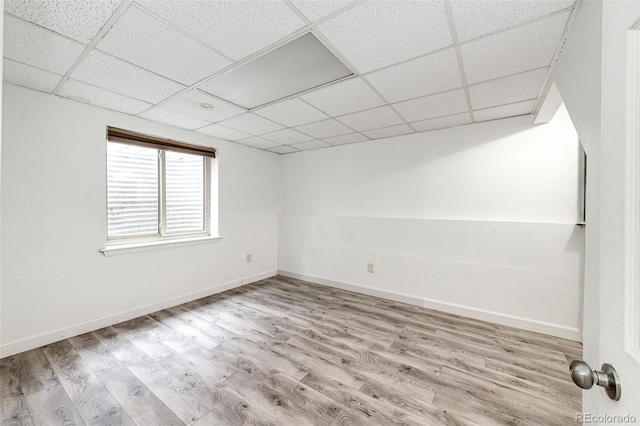 empty room featuring baseboards, a drop ceiling, and wood finished floors