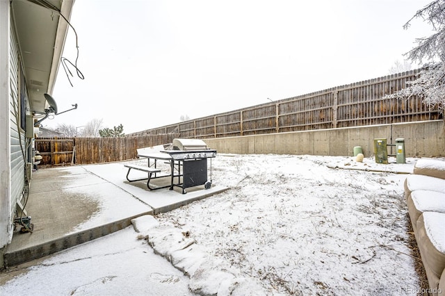 yard covered in snow with a fenced backyard and a patio