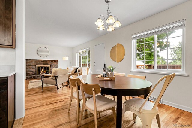 797 W Briarwood Ave, Littleton, CO 80120 - dining space featuring light wood-type flooring, a chandelier, a brick fireplace, and baseboards