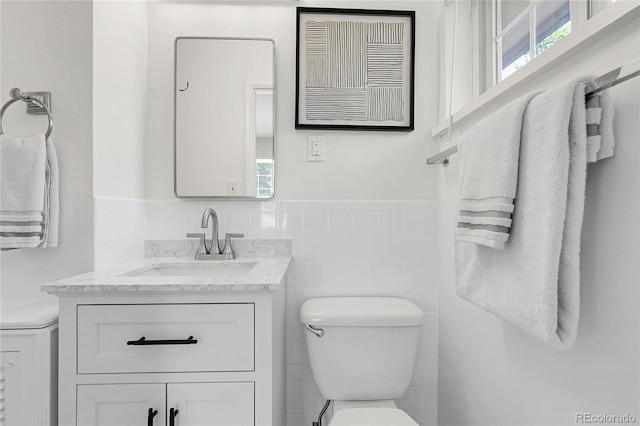 797 W Briarwood Ave, Littleton, CO 80120 - half bath featuring toilet, vanity, plenty of natural light, a wainscoted wall, and tile walls
