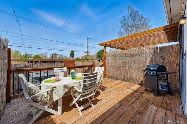 wooden terrace featuring a fenced backyard, a grill, and outdoor dining space