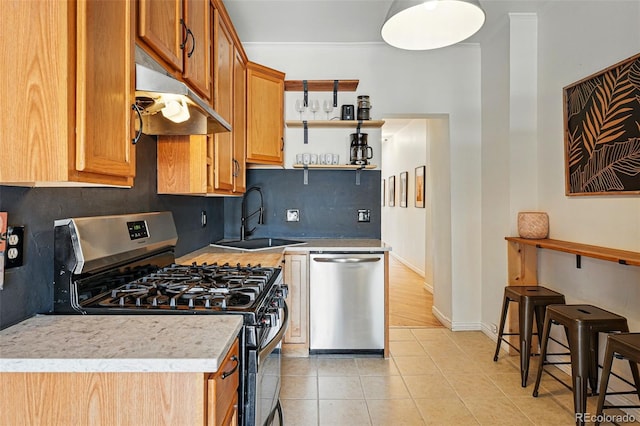 kitchen with light tile patterned flooring, under cabinet range hood, a sink, backsplash, and stainless steel appliances