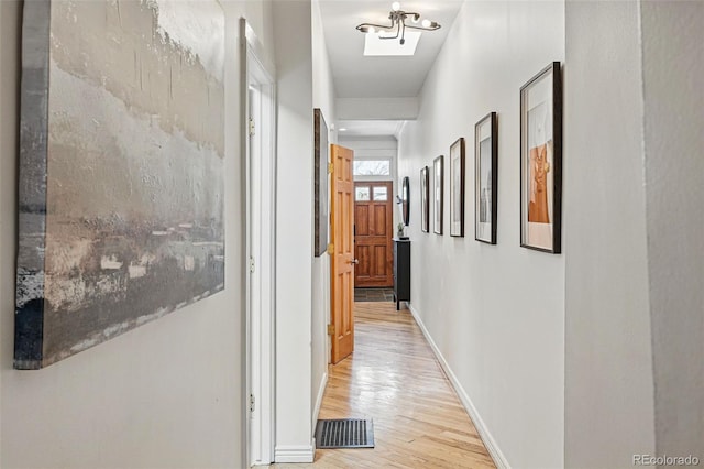 corridor featuring light wood-type flooring, baseboards, and visible vents