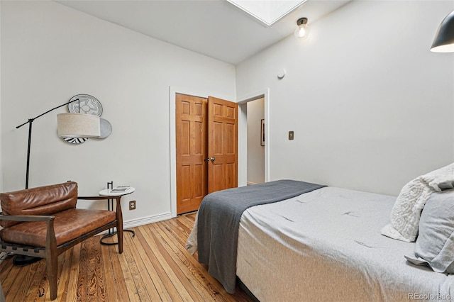 bedroom featuring a skylight, baseboards, and light wood-style floors