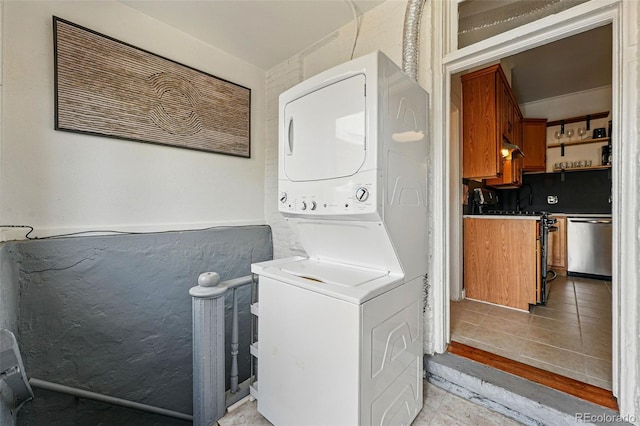 laundry area featuring stacked washing maching and dryer, laundry area, and light tile patterned flooring