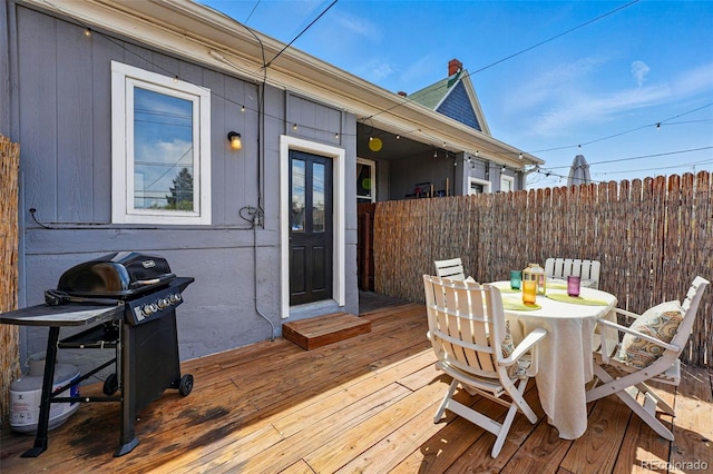 wooden deck with fence, outdoor dining area, and a grill