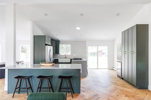 kitchen with light parquet floors, stainless steel fridge, a kitchen breakfast bar, and a wealth of natural light