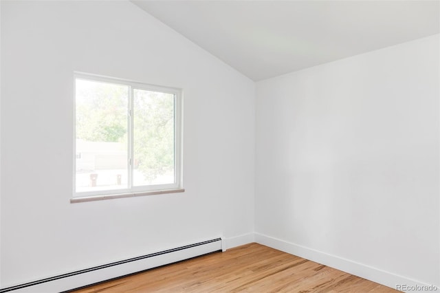 empty room with light hardwood / wood-style flooring, baseboard heating, vaulted ceiling, and a wealth of natural light