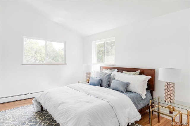 bedroom with a baseboard radiator, vaulted ceiling, and hardwood / wood-style flooring