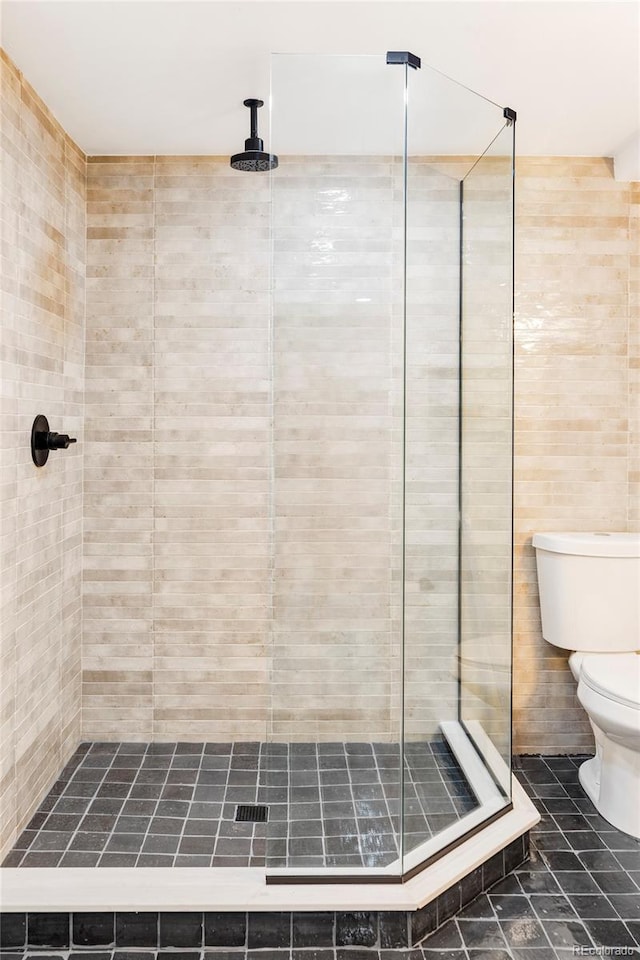 bathroom with a tile shower, tile walls, and toilet