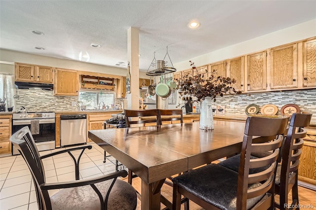 dining room with a textured ceiling, a wealth of natural light, light tile patterned floors, and recessed lighting