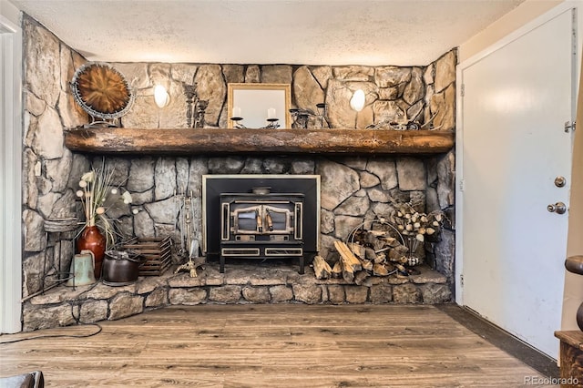 room details with a wood stove, a textured ceiling, and wood finished floors