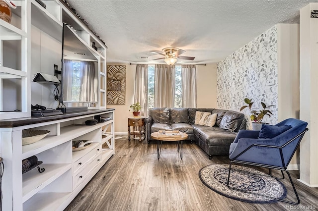 living room with a textured ceiling, baseboards, ceiling fan, and dark wood-style floors